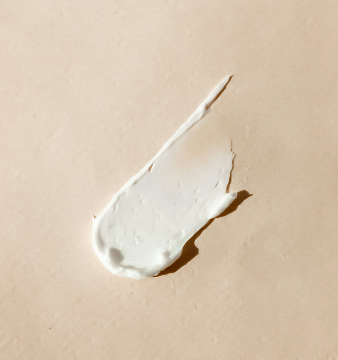 White cream smear on beige background representing discovering soothing solutions to common sensitive skin problems