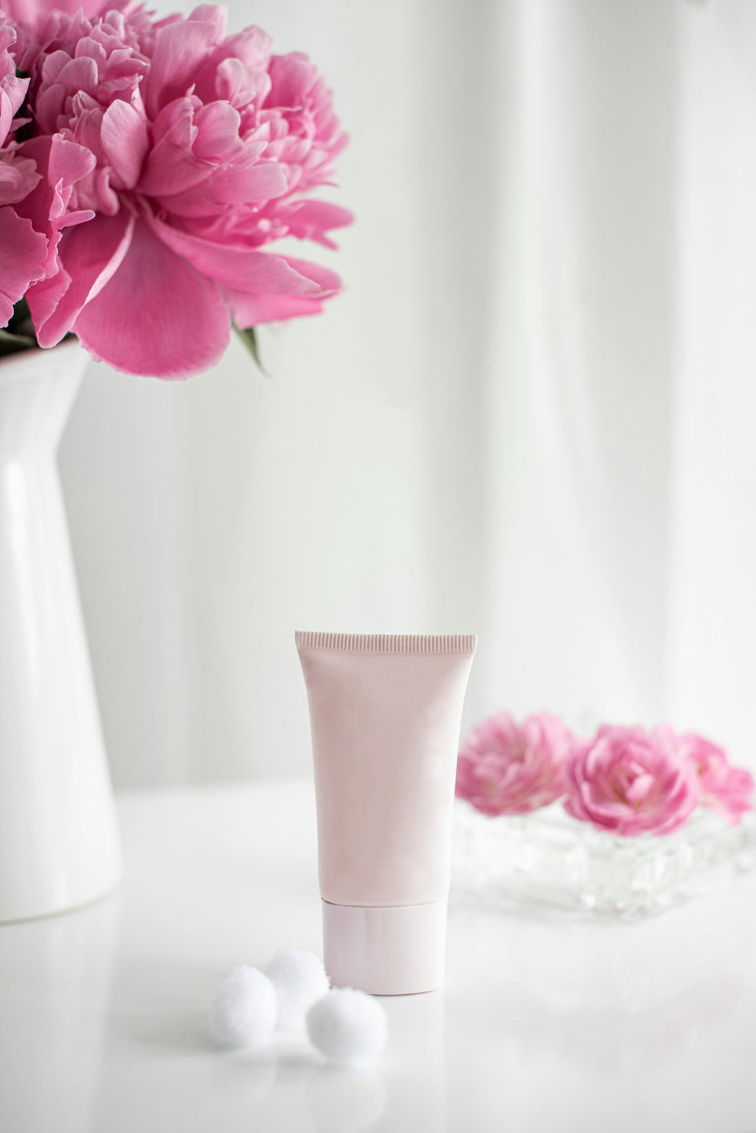 How to Personalize Your Skincare Regimen for Optimal Results with pink cream tube and flowers on white surface