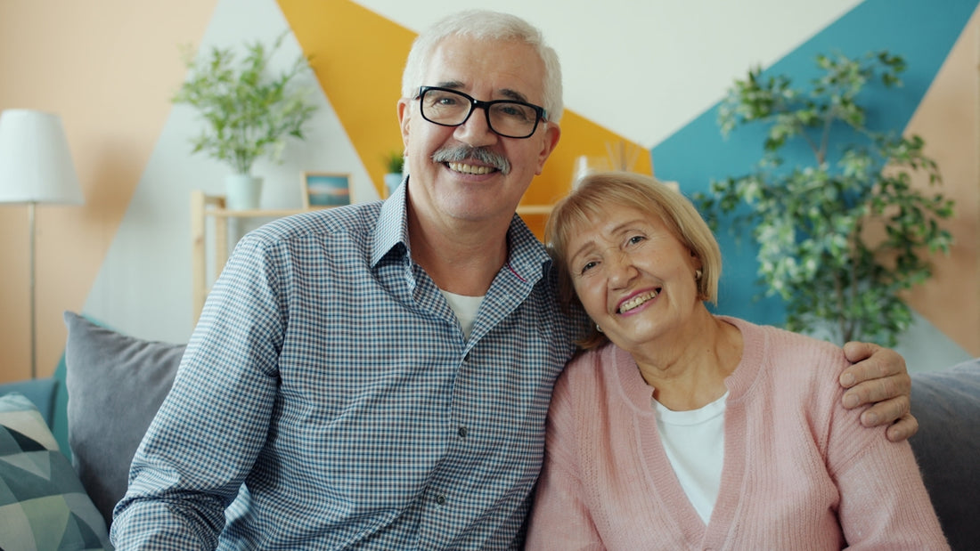 Elderly couple smiling together on a couch.