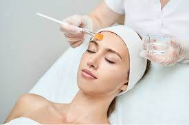 Relaxed woman receiving a facial treatment with a brush and soothing gel.