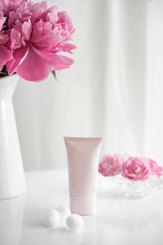 Simple skincare routine checklist featuring a cream tube, cotton balls, and fresh flowers